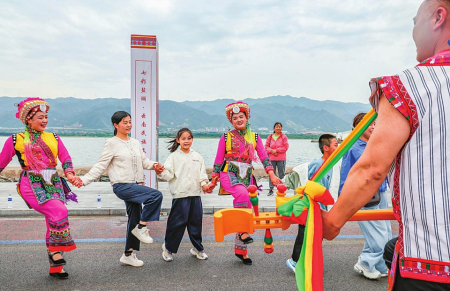 5月1日,在盐湖景区,来自云南彝族的演员身着盛装和游客们载歌载舞欢度假期。 配图2
